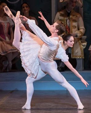 Ballet dancers performing on stage with a classical ballet setting.