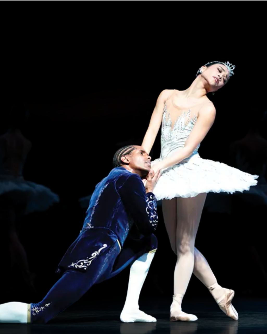 Ballet dancers in performance of Swan Lake on a dark stage