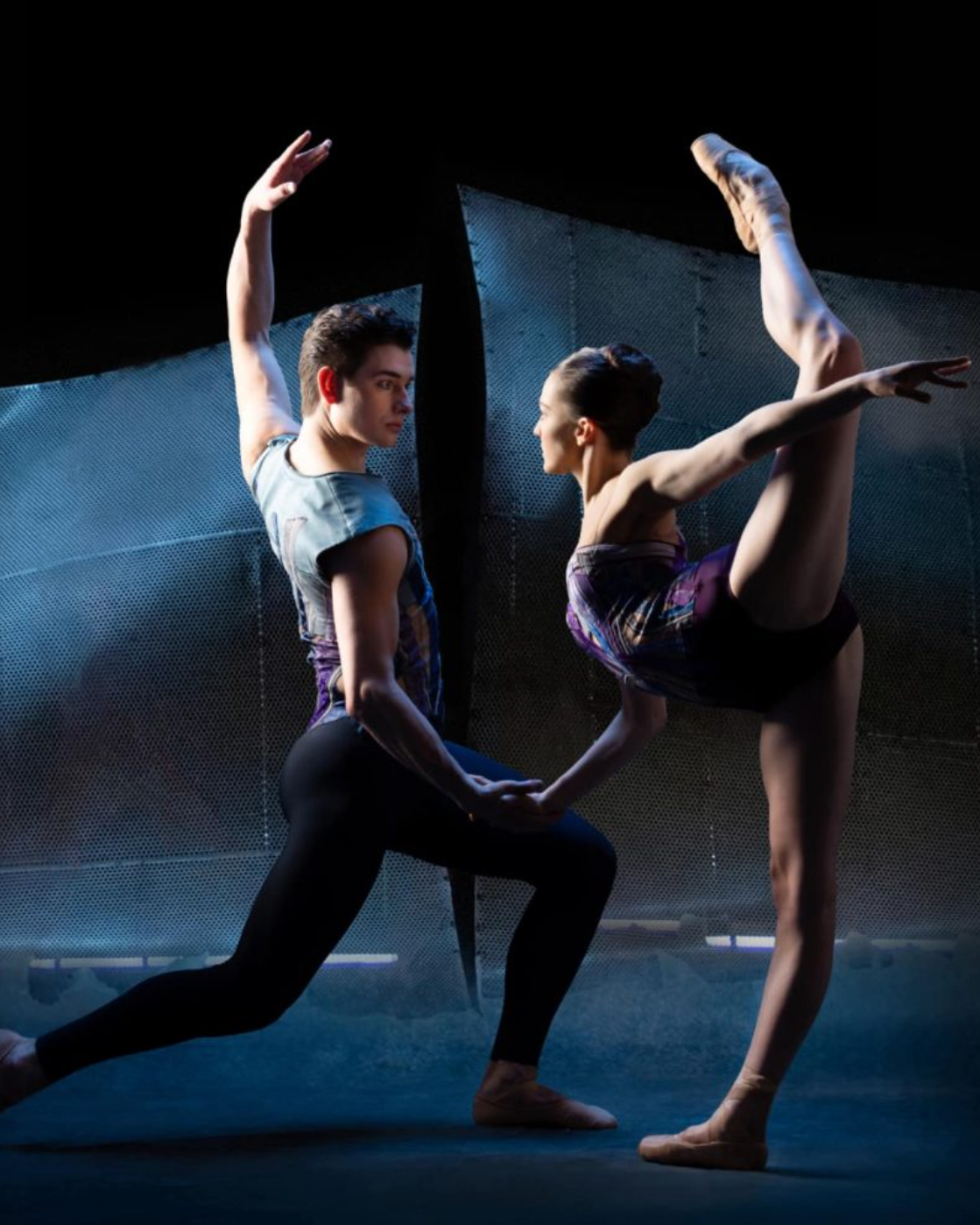 Two dancers in a dramatic pose on a dark stage
